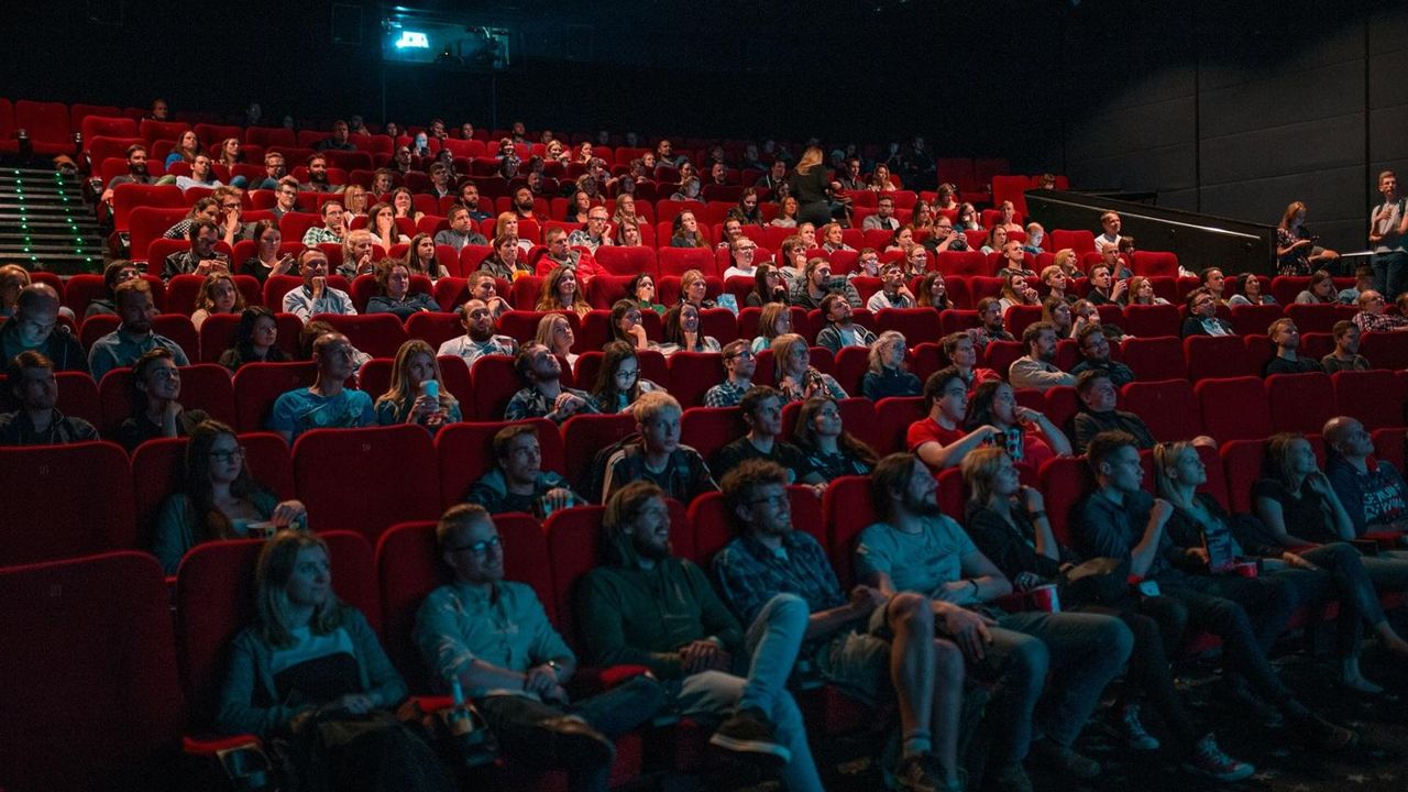 Des personnes sont assises dans les fauteuils d'une salle de cinéma
