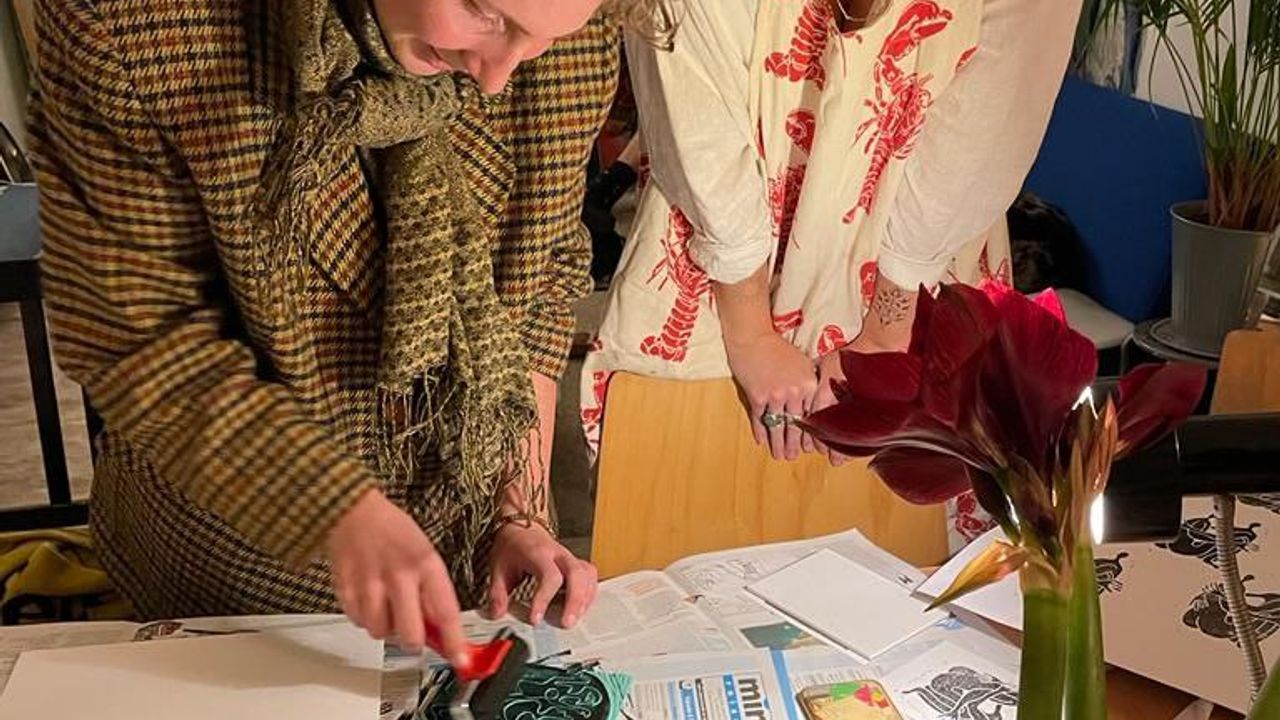 two people lino-printing a postcard