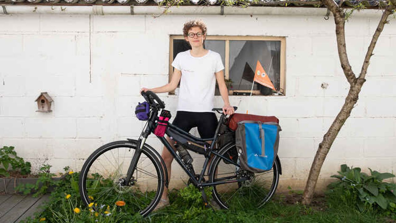 Valentine Crespon pose dehors dans un jardin avec son vélo.