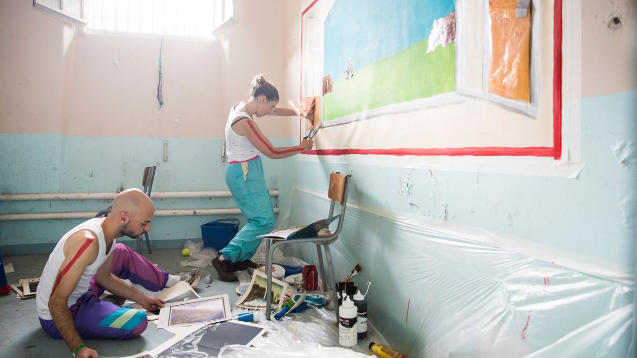 des artistes peignent un tableau sur le mur  dans une cellule
