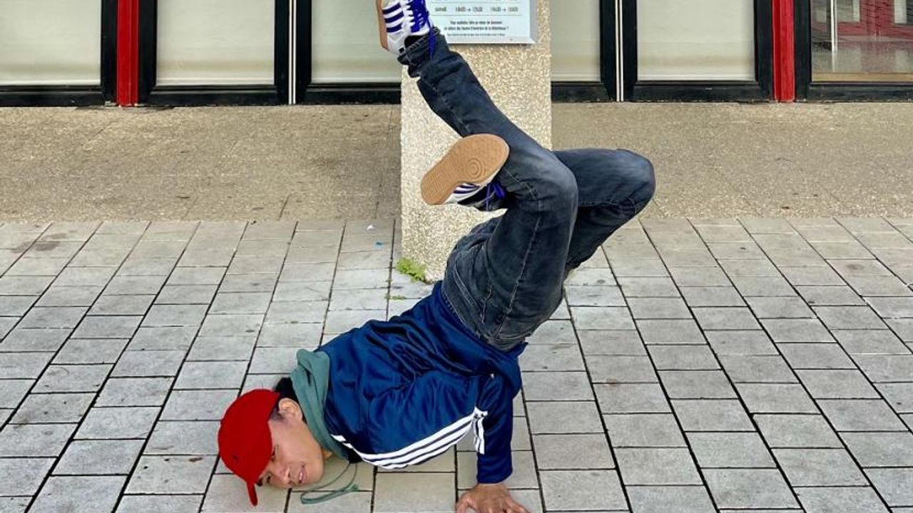 Le chorégraphe Bruce Chiefare en posture de hip hop tête au sol, jambes en l'air